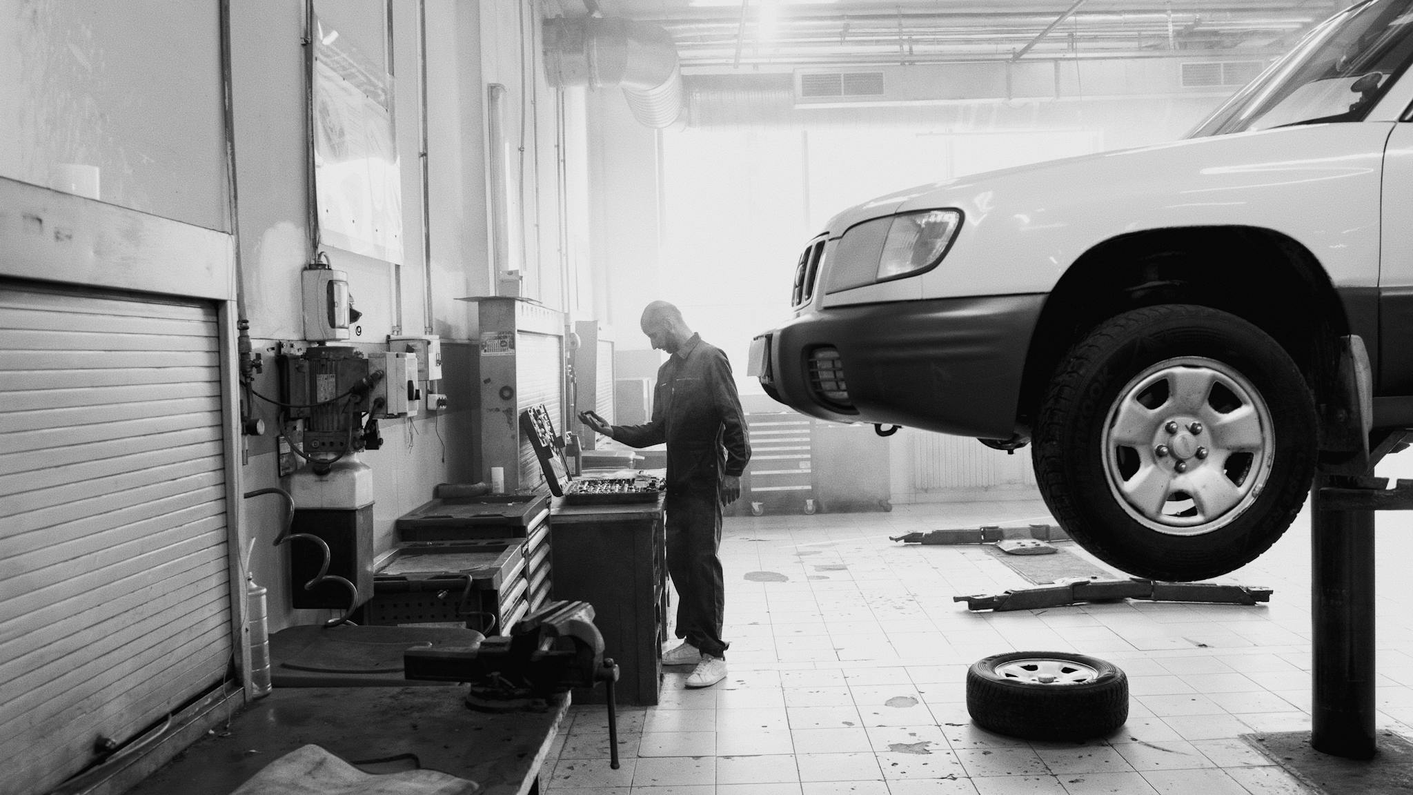 Black and white image of a mechanic working in an auto repair shop.